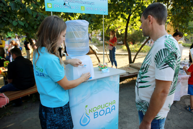 На фото работница компании «Корисна вода» по доставке питьевой воды на дом и офис бесплатно раздает воду на фестивале в Черкассах